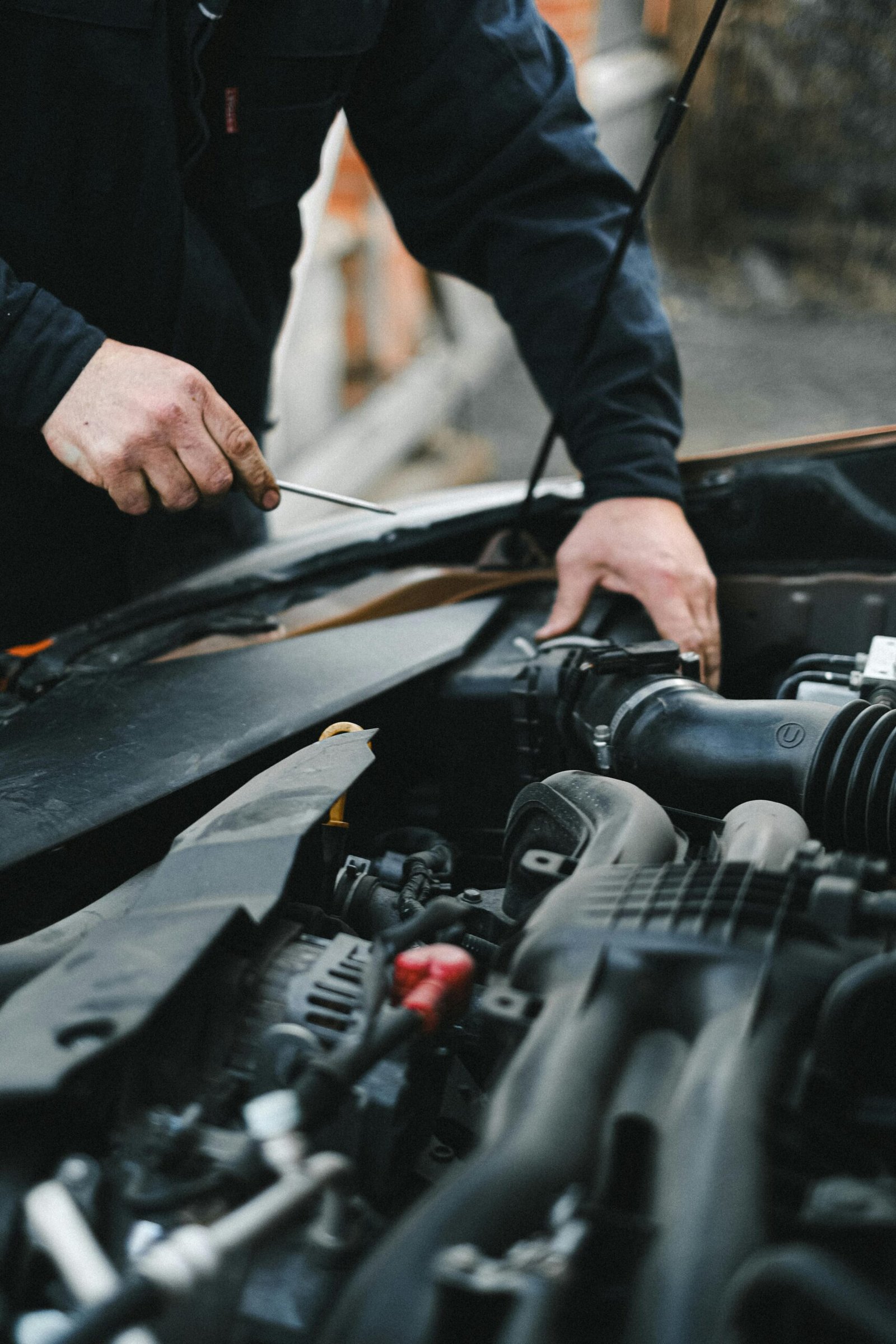A mechanic working on a car engine with tools, focused on repairs.